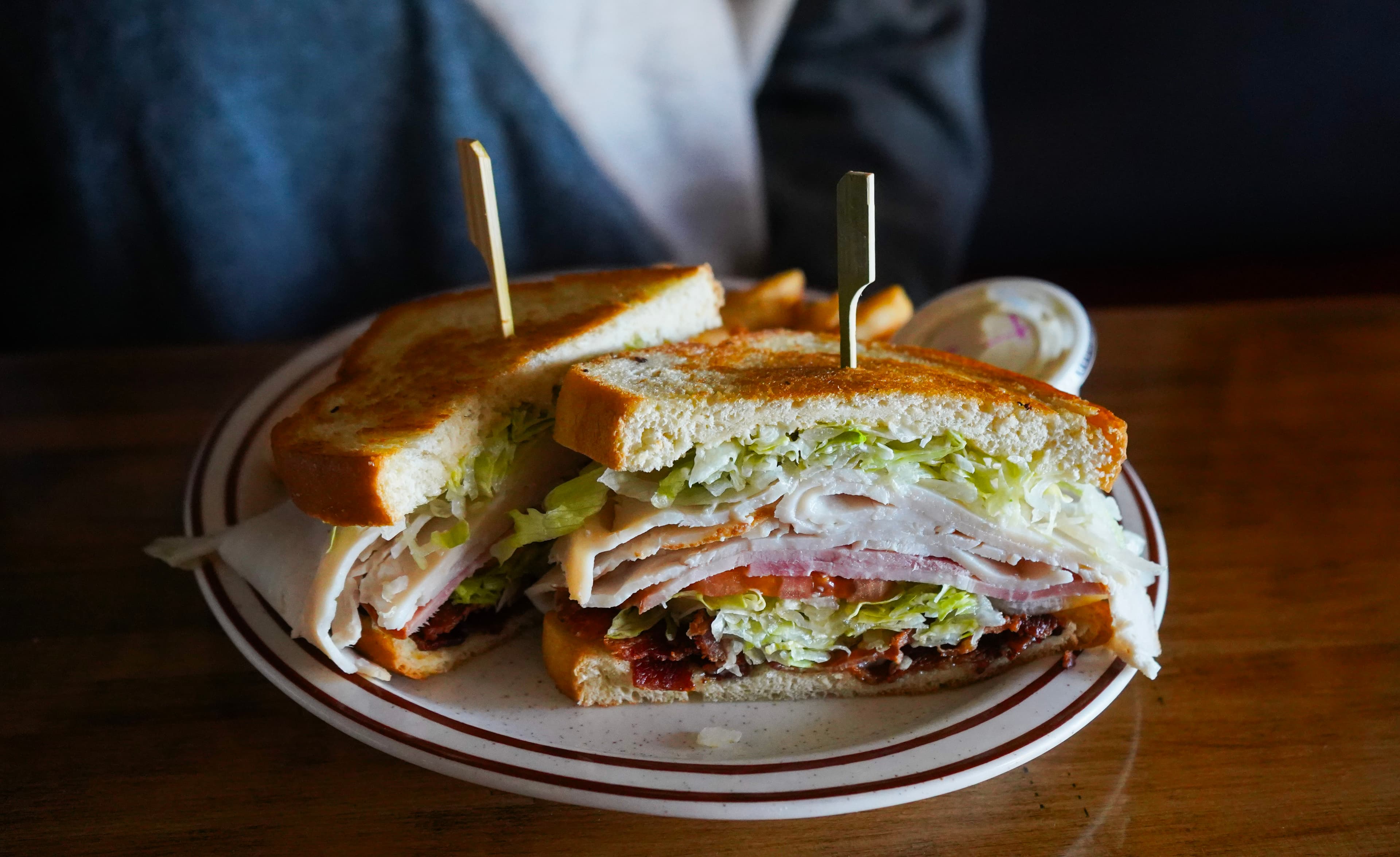 A stacked turkey club sandwich on toasted bread at the Beach House