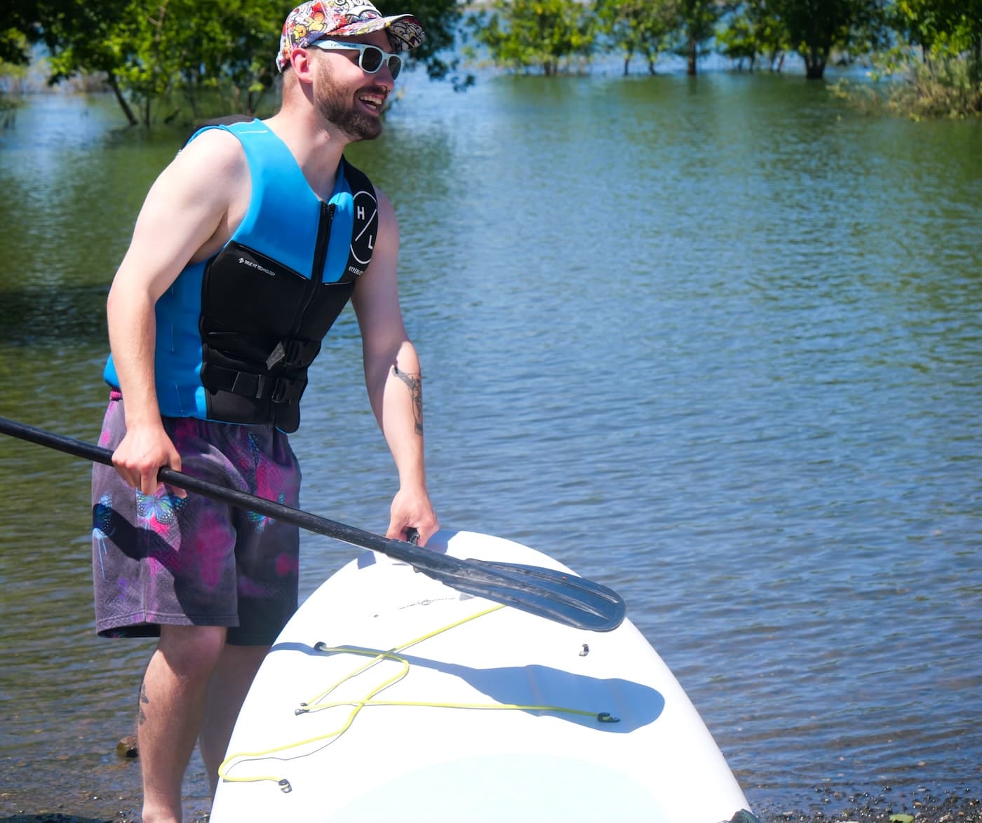A paddler in a life vest walking his board into the shallows
