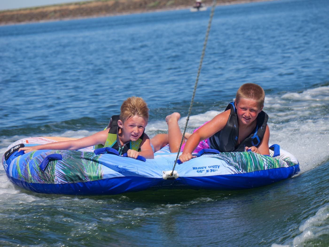 Two kids hanging onto a tube behind a boat on Potholes Reservoir