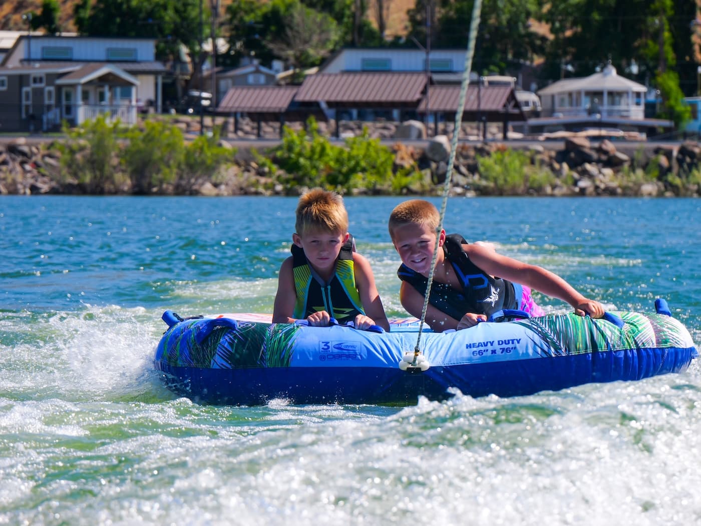 Two kids on a tube passing the resort shoreline