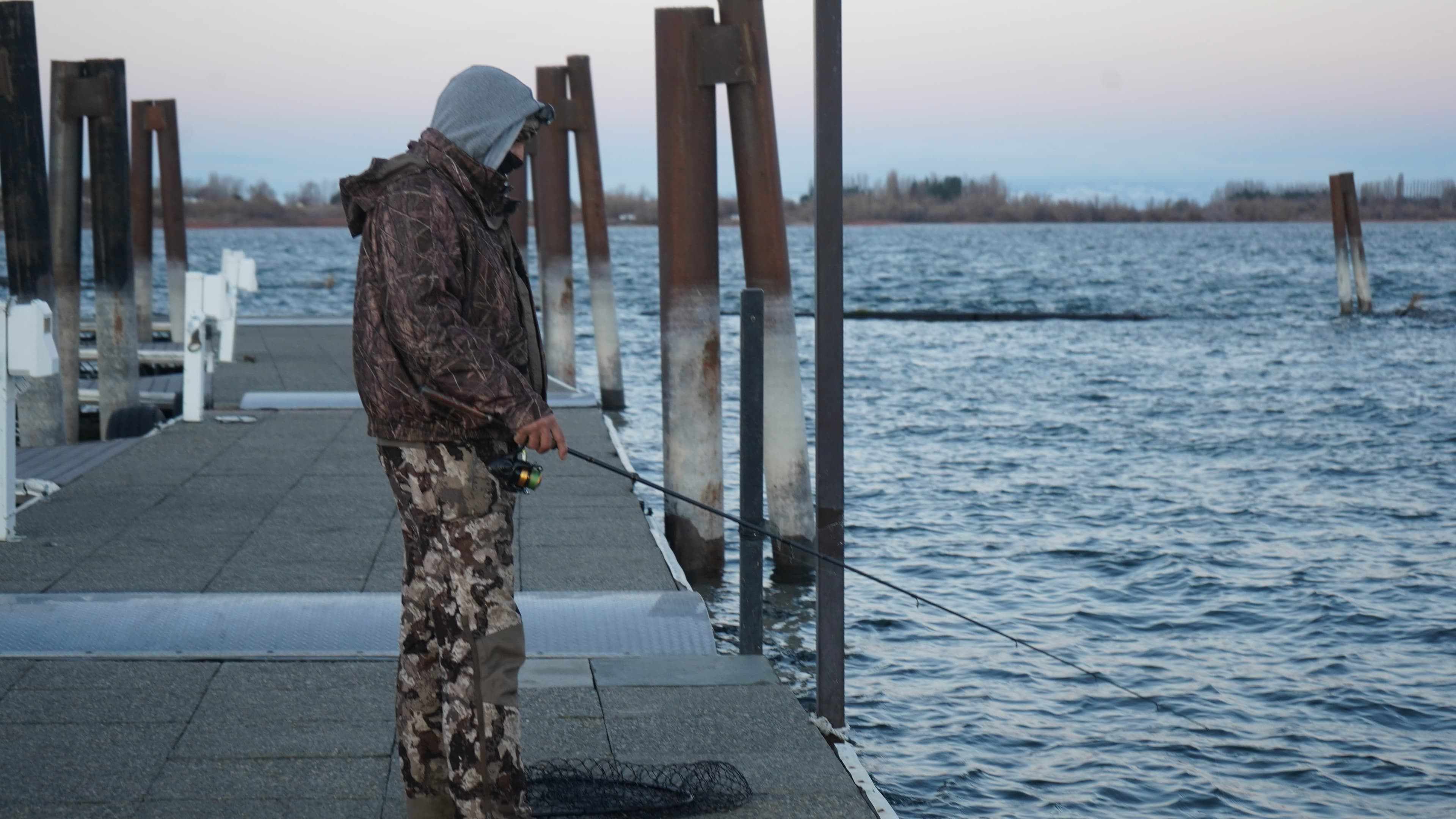 An angler fishing from the dock on Potholes Reservoir, landing net at their feet