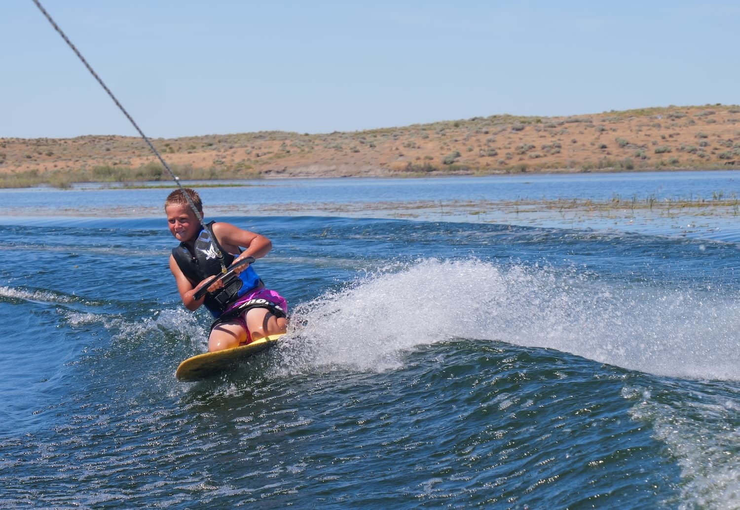 A kid knee-boarding on the water