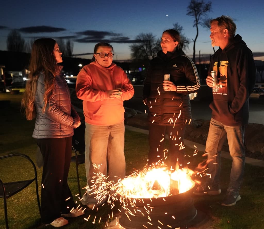Guests gathered around a lakeside campfire in the evening